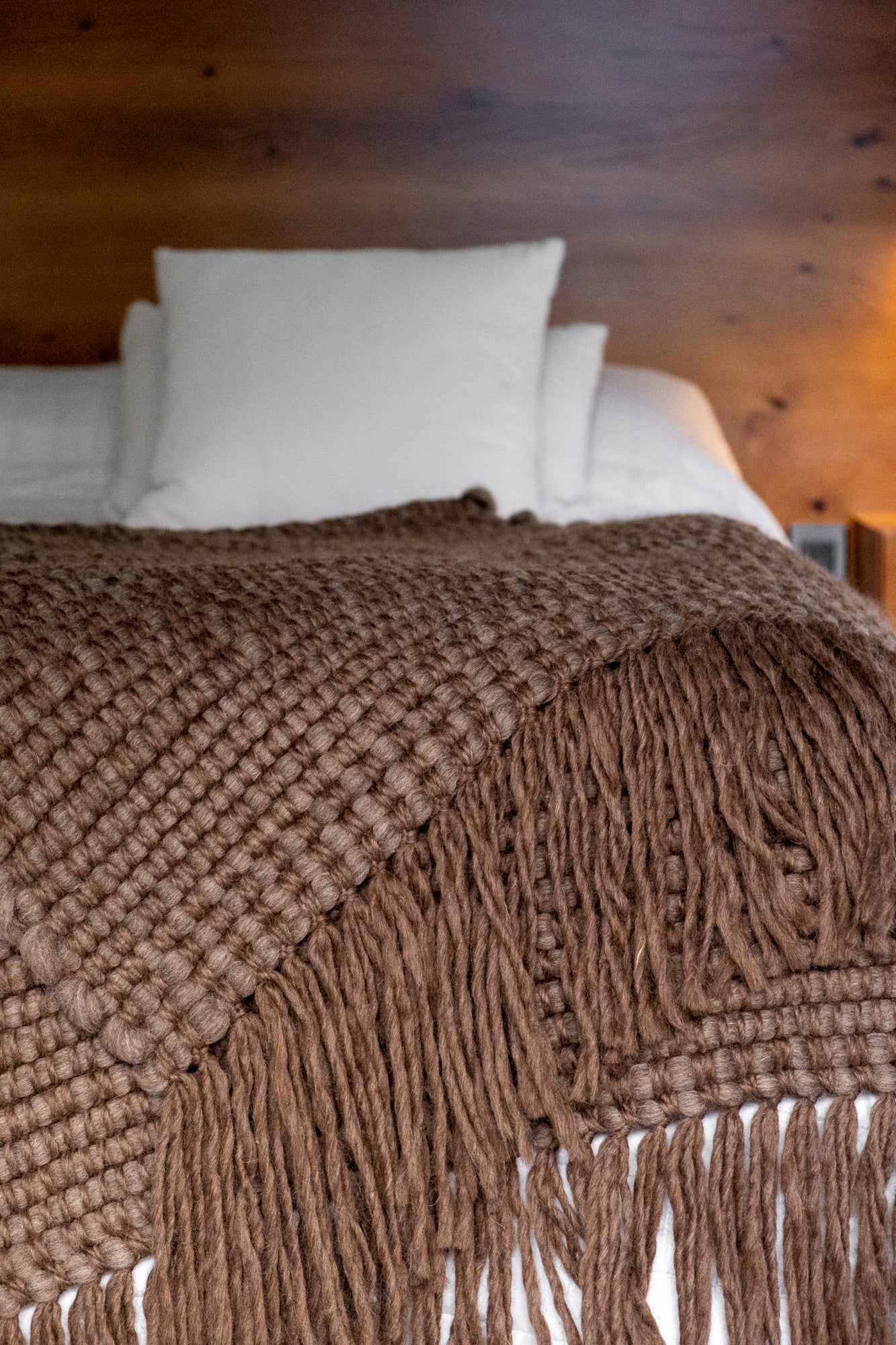 Manta Terra de lana natural marrón tejida en telar, colocada al pie de la cama